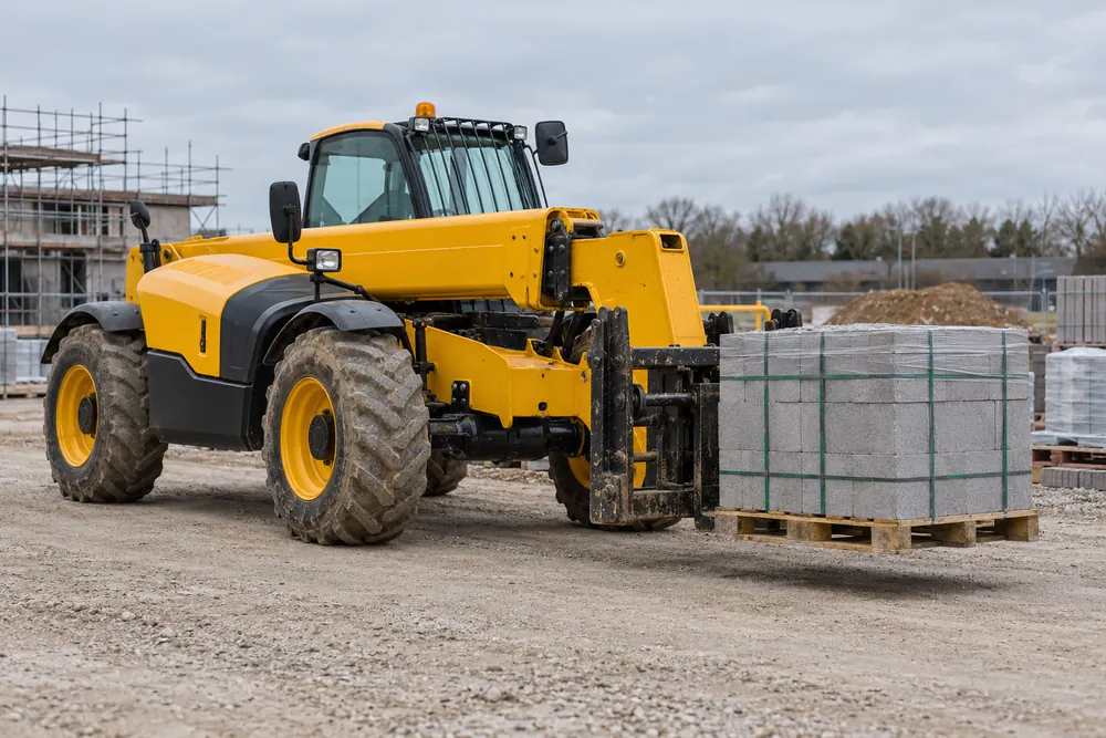 Telehandler handling a pallet of building blocks in a construction compound
